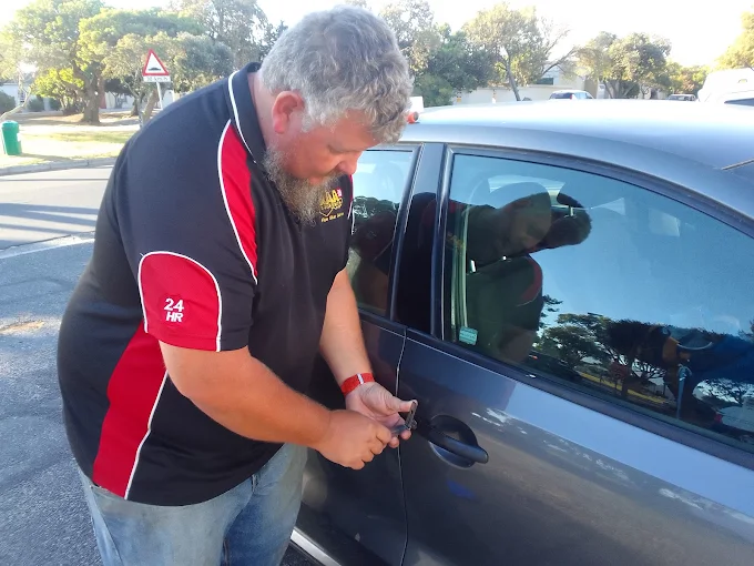An AAA Locksmiths technician opening a locked car door at the roadside